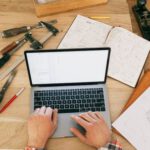 Top Trading Tools - A Person Using a Laptop While on the Carpentry Workbench